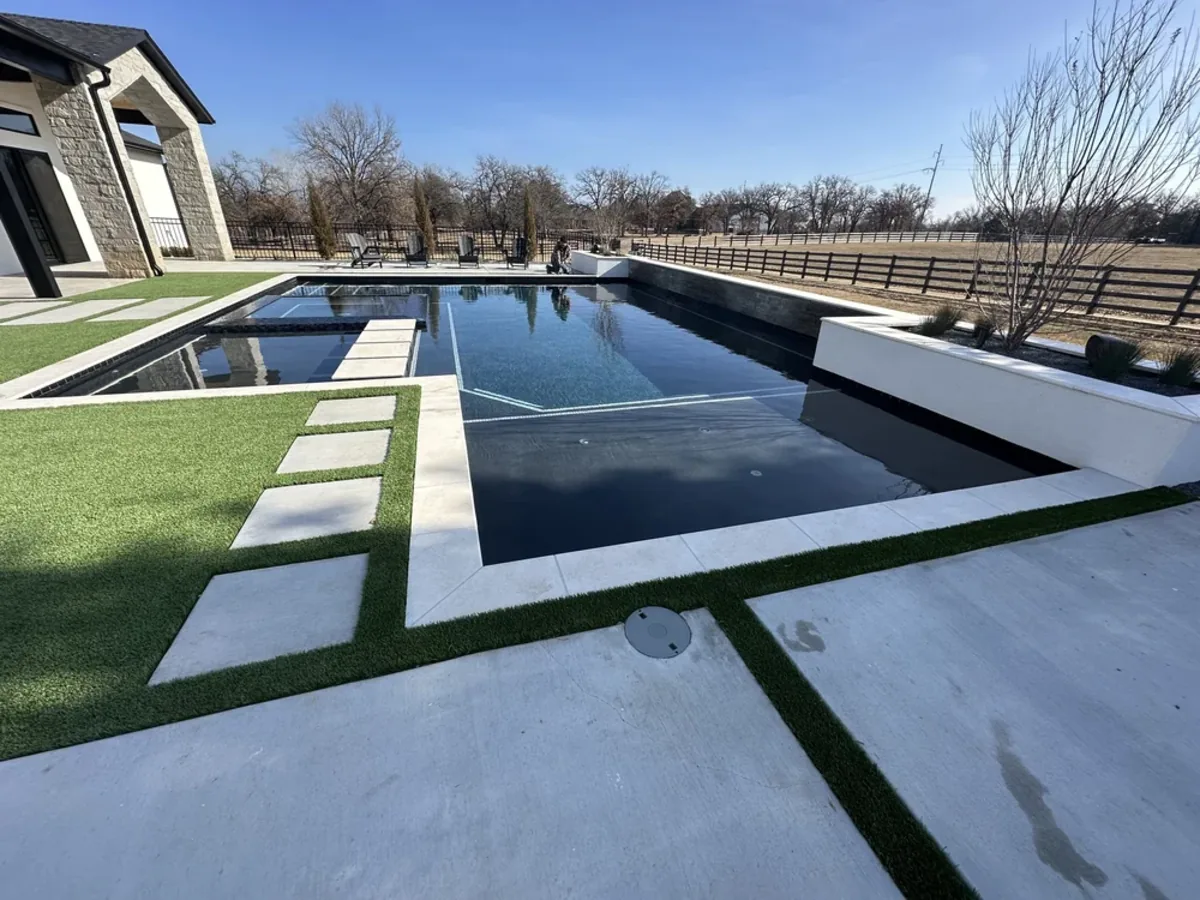 Dark bottom pool with turf and concrete banded deck in Oklahoma City
