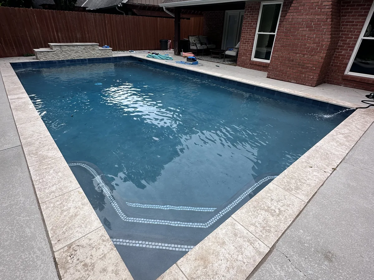 Geometric pool with sun ledge and travertine coping