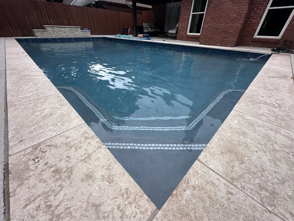 Geometric pool with travertine coping and step entry