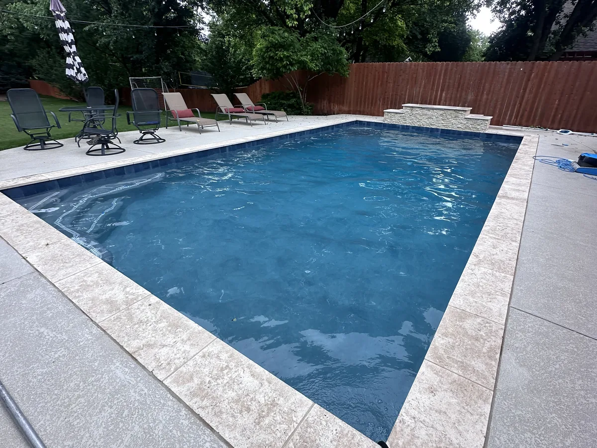 Geometric pool with travertine deck and turf lawn