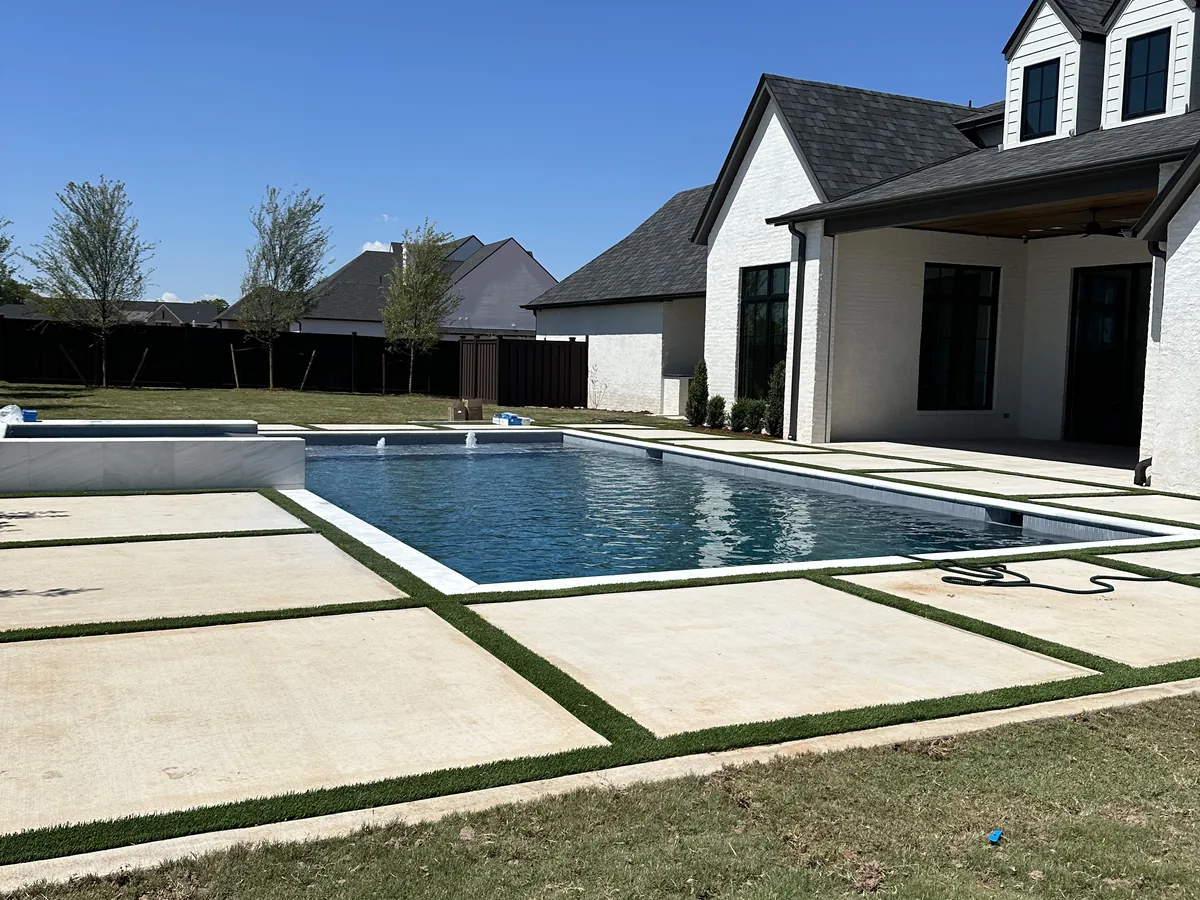 Rectangular pool and concrete deck behind a home