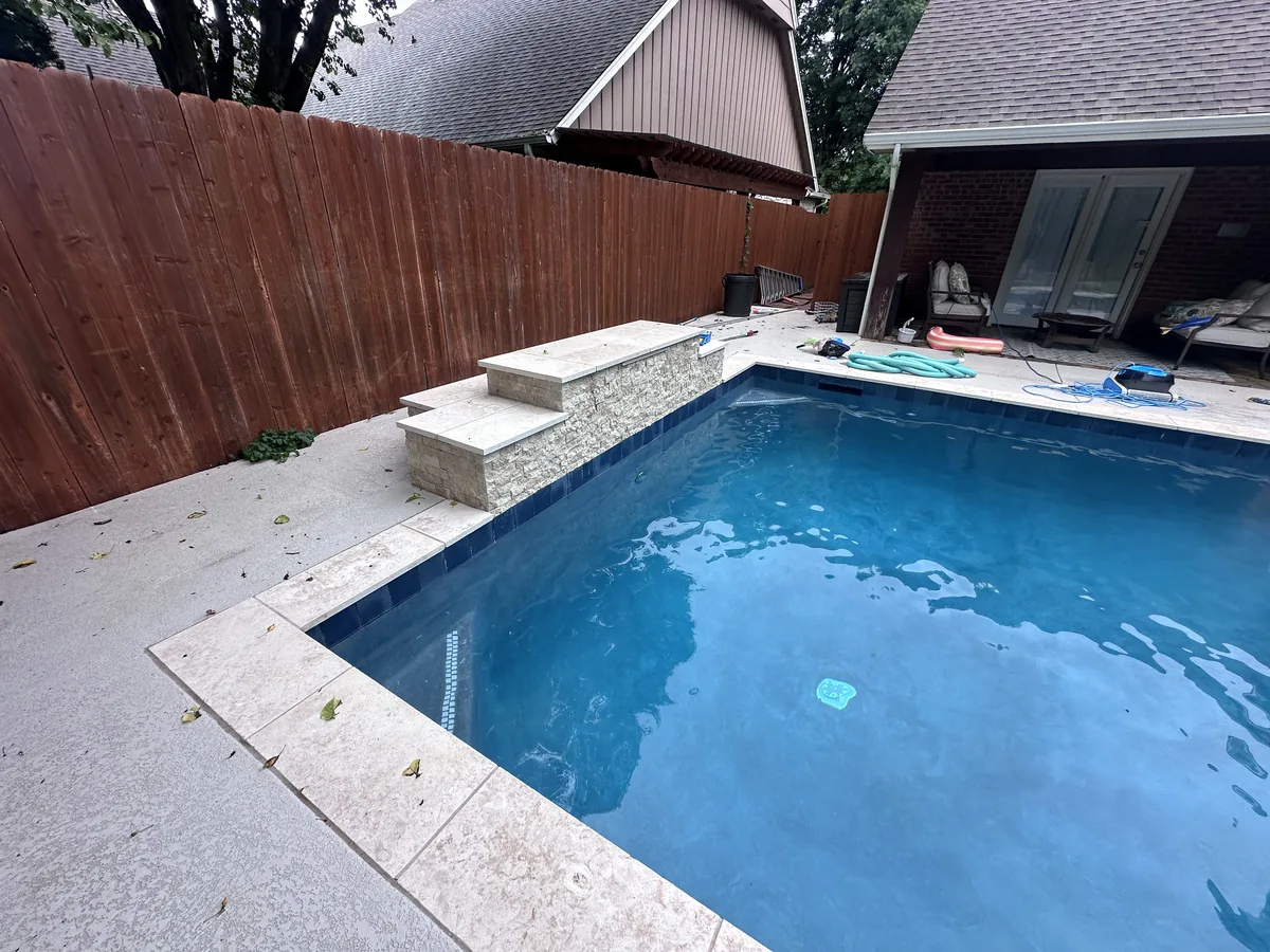 Rectangular pool with travertine deck and privacy fence